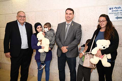 Senator Bolsonaro presents big white teddy bears to two children who are patients at Hadassah.